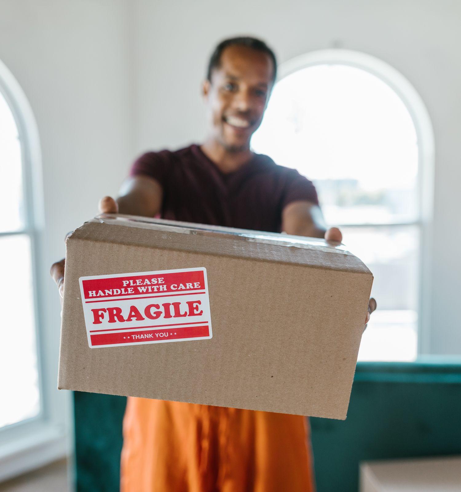 A mover holding a box labelled please handle with care